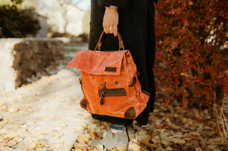 holding an orange della q makers midi backpack