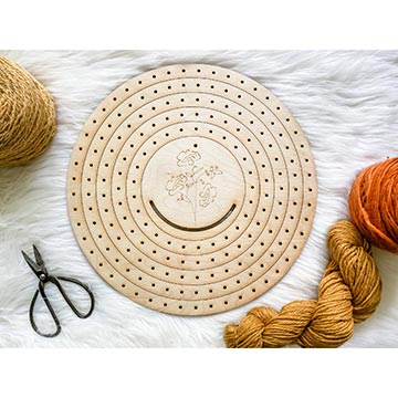 Circle loom with scissors and a hank of yarn