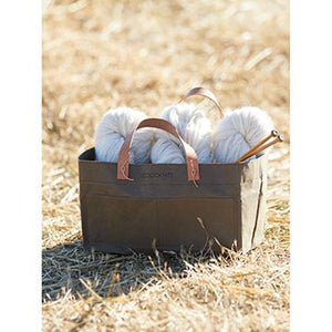 Cocoknits Kraft Caddy filled with yarn sitting outside in a field