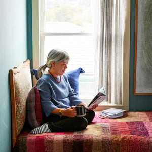 Woman sitting on bed with marled throw