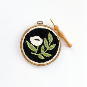 Completed black floral punch needle kit with a white background