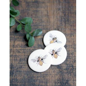 Image of ceramic bee buttons on wood table