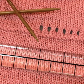 gauge ruler with magnification on sweater with knitting needles